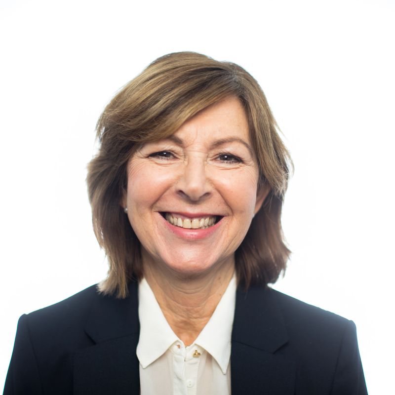 Close-up portrait of cheerful senior businesswoman on white background. Senior female entrepreneur in suit smiling at camera.