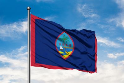 Guam flag on pole with blue sky behind it