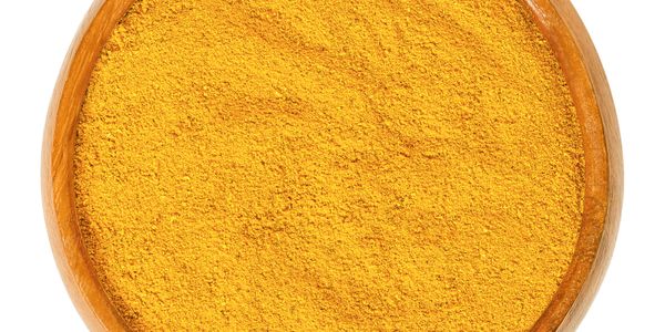 Wooden bowl filled with bright yellow turmeric powder.