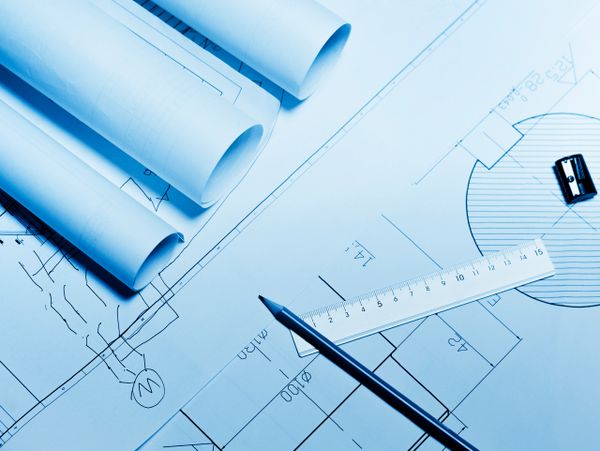 Architectural blueprints with ruler and pencil on a desk.