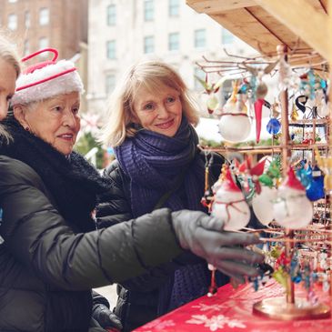 Two elderly women shopping for Christmas ornaments outdoors.