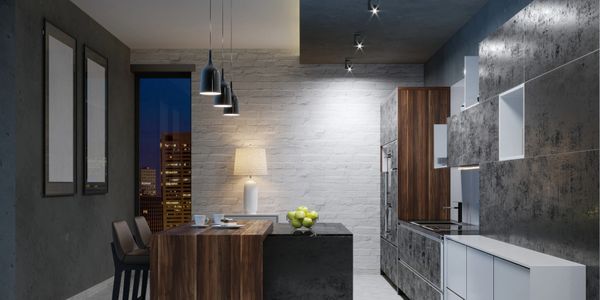 Modern kitchen with dark wood and concrete finishes, illuminated by pendant and ceiling lights.