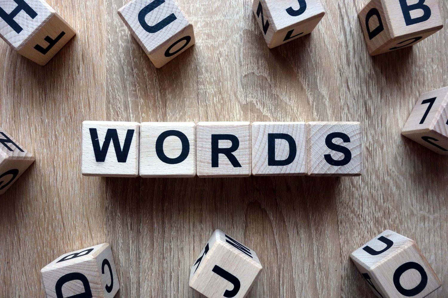 Wooden blocks spelling the word 'WORDS' on a wooden surface.