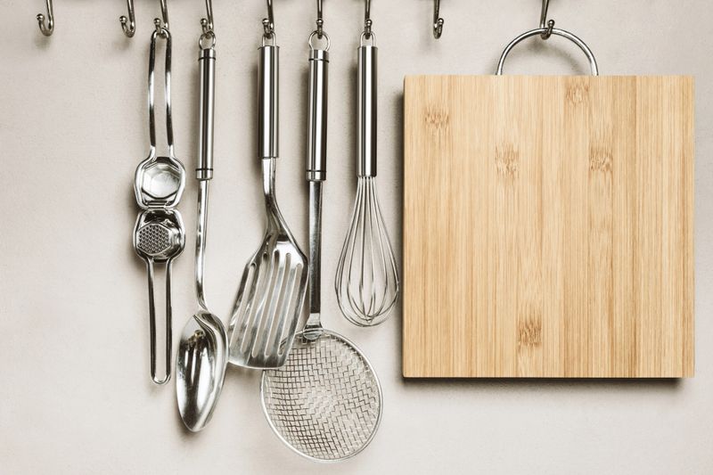 Kitchen detail, utensils for cooking hanging with hooks on the wall