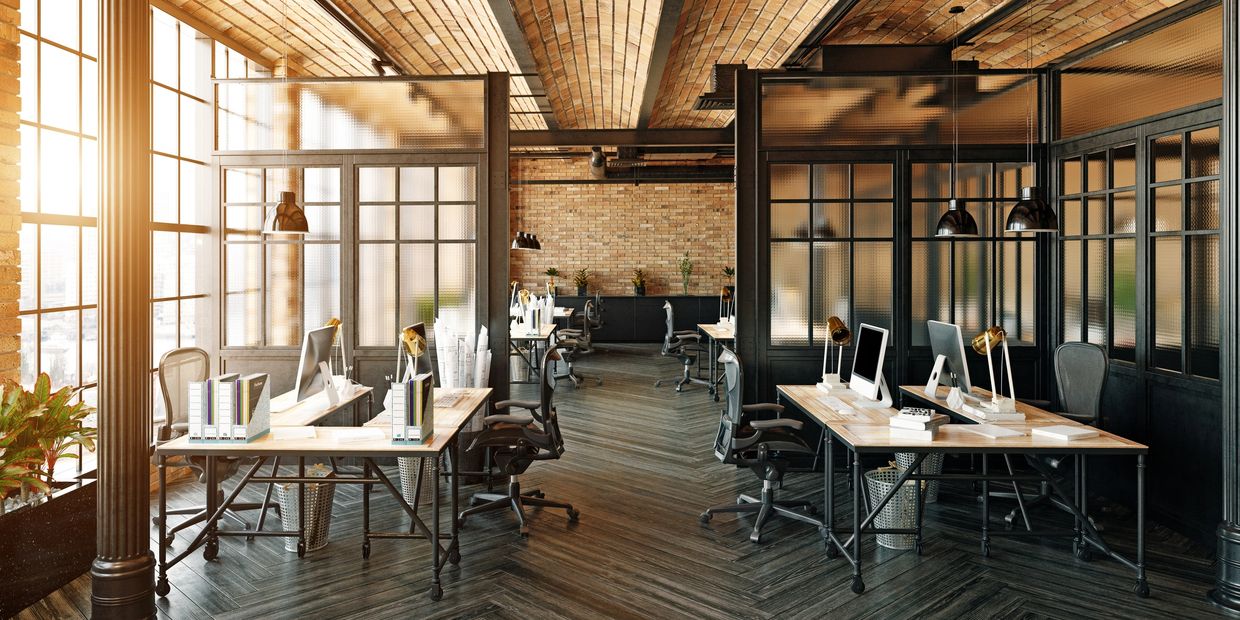 Modern industrial-style office with brick walls and wooden desks.