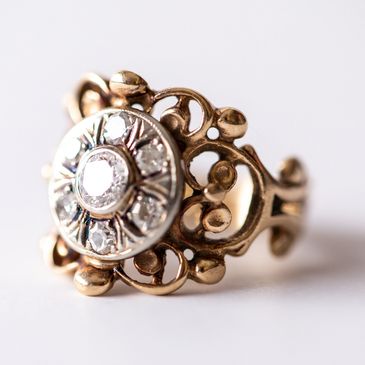 Close-up of an ornate vintage gold ring with a central diamond and intricate design.