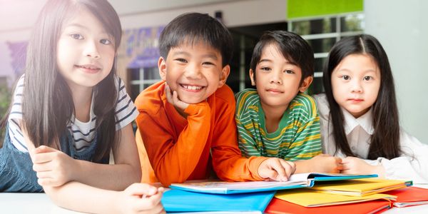 Four kids smiling and lying on the floor with books.