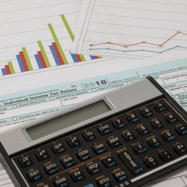 Calculator and tax documents with financial charts in the background.