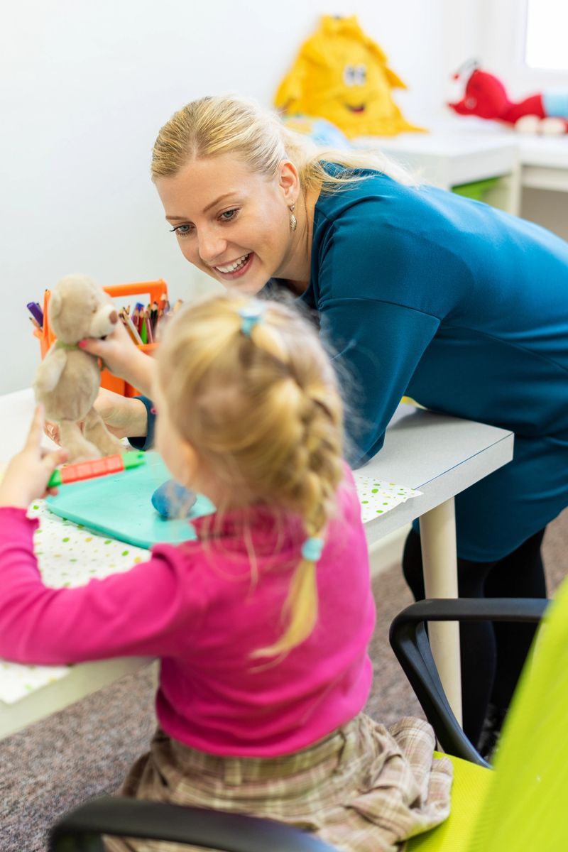 Toddler girl in child occupational therapy session doing sensory playful exercises with her therapist.