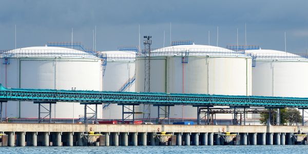 Large white industrial storage tanks near a waterfront.