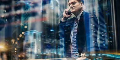 Businessman on phone with city lights reflection at night.