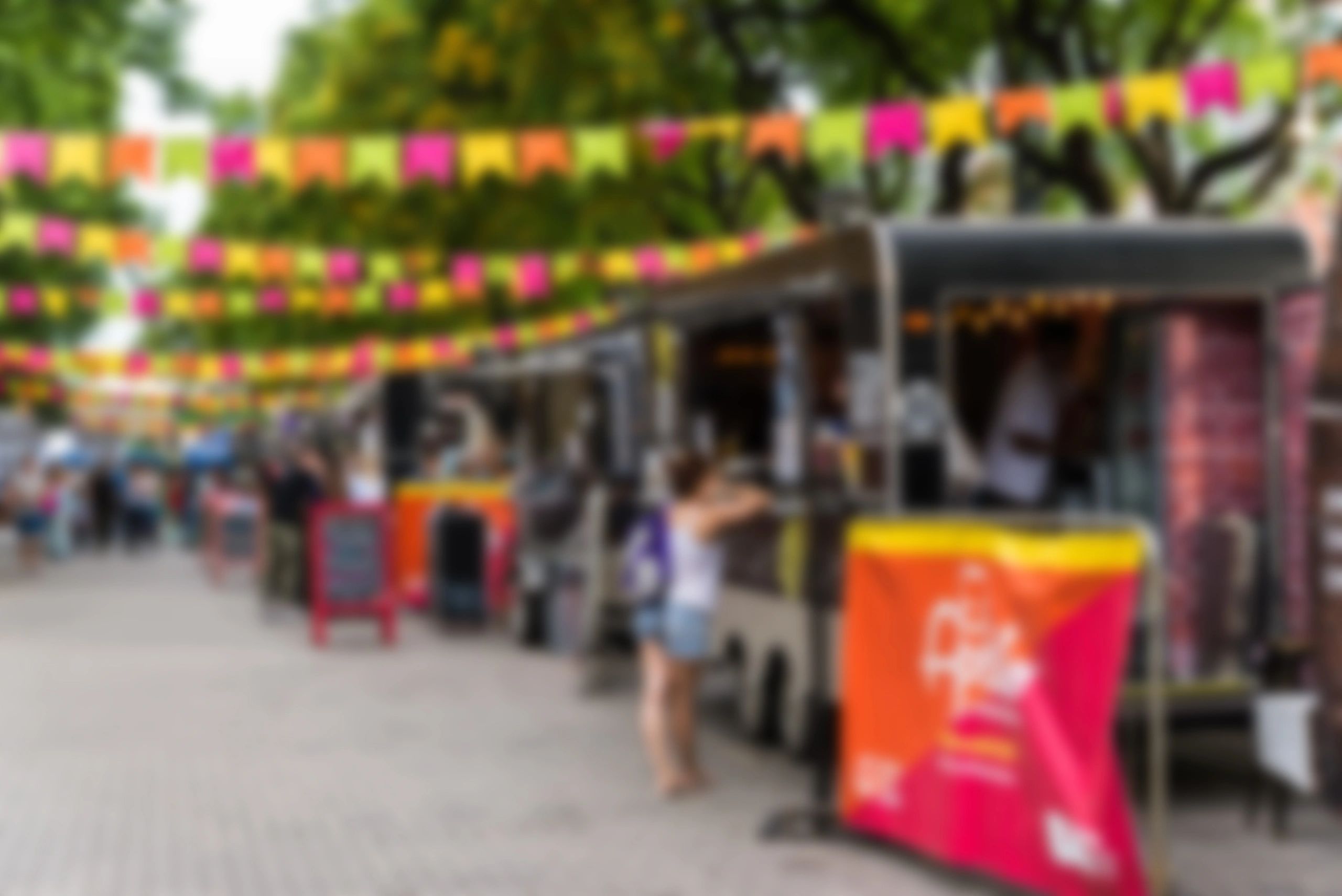 Outdoor market with colorful flags and food trucks.