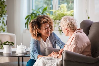 Friendly caregiver assisting a senior woman with hair brushing in a home-like setting