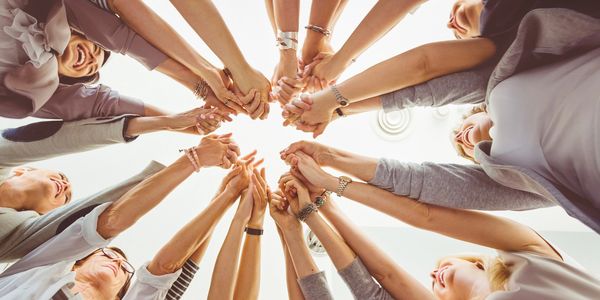 A diverse group of people standing in a circle holding hands together.