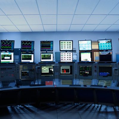 Control room with multiple monitors displaying various data and graphs.