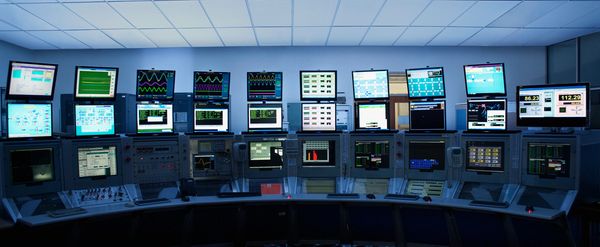 Control room with multiple monitors showing data and graphs.