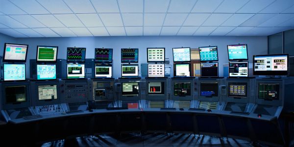 A control room with multiple monitors displaying data and graphs.