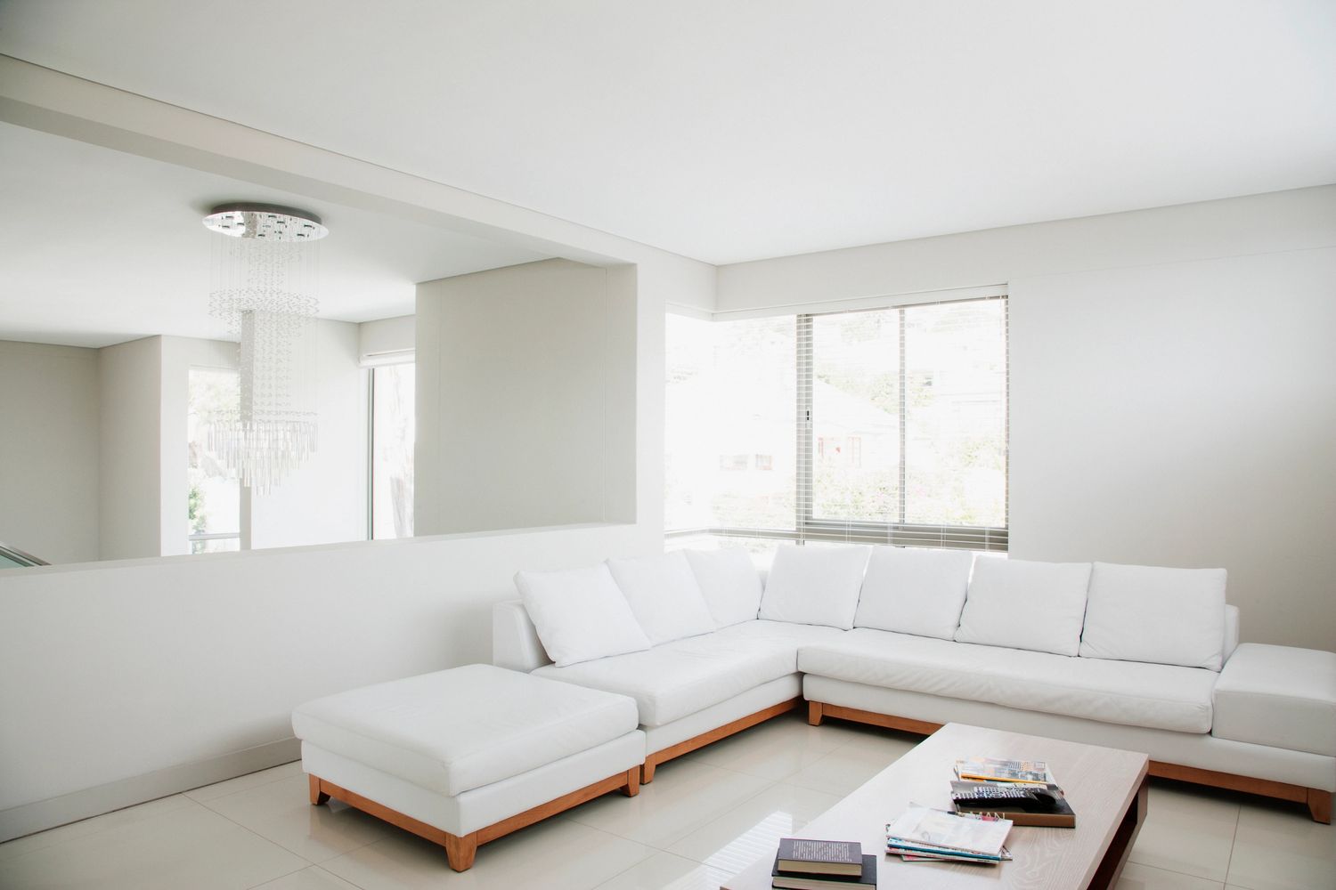 Bright modern living room with white sectional sofa and wooden coffee table.