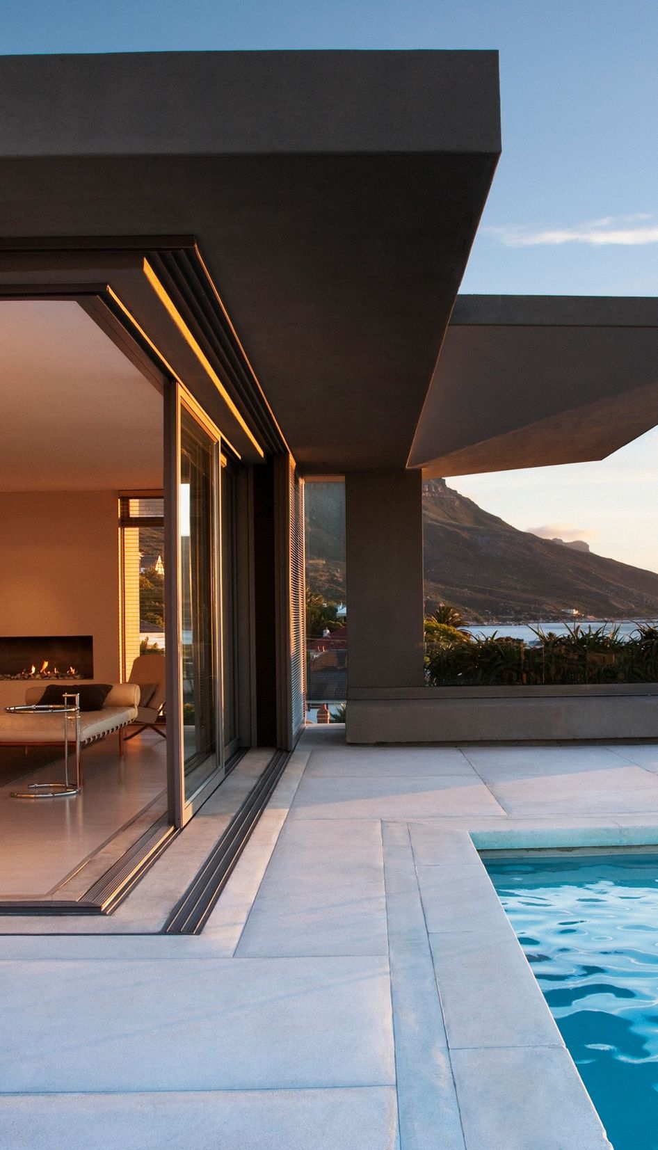 Modern home with a fireplace and pool overlooking a mountain.