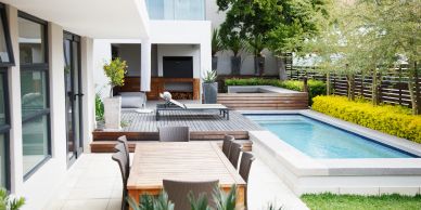 Modern backyard with pool, seating, and dining area.