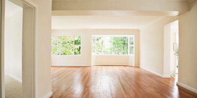 Empty bright room with wooden floor and large windows.