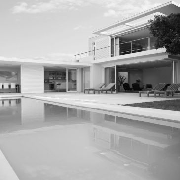 Modern house with pool and lounge chairs.
