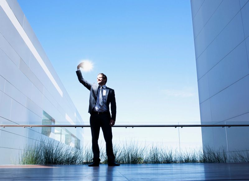Businessman holding glowing light on balcony