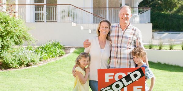 Happy family celebrating in front of their sold home.