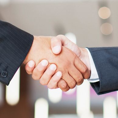 Two people in business suits shaking hands.