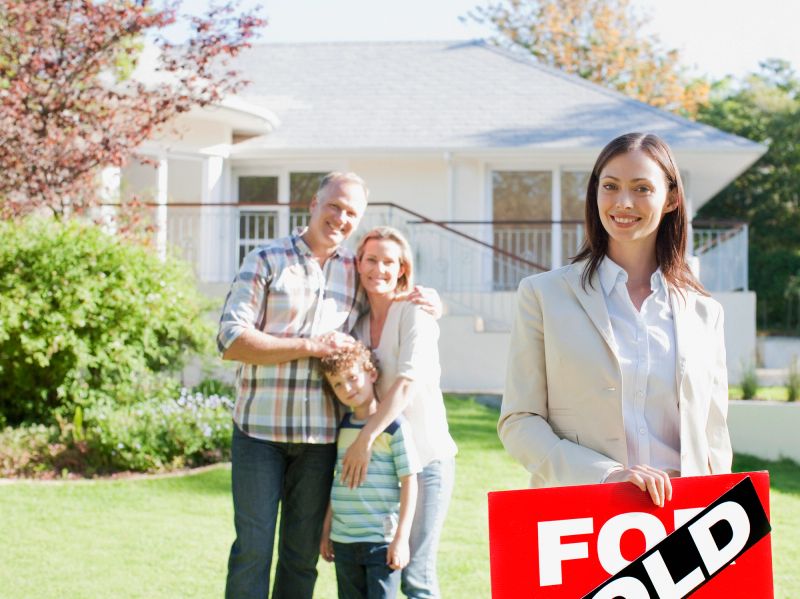 Real Estate Agent standing with family in front of new house