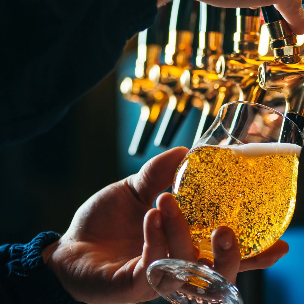 Person pouring a draft beer into a glass.