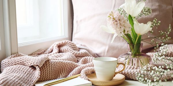 Pretty pink and cream scene with flowers, tea and a journal and pen