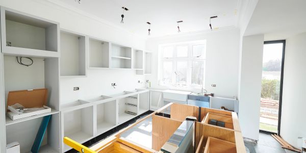 Unfinished kitchen with white cabinets and bare shelves.