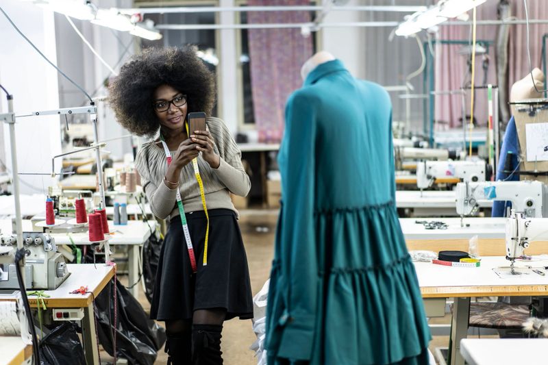 Female designer with tape measure working in fashion studio.