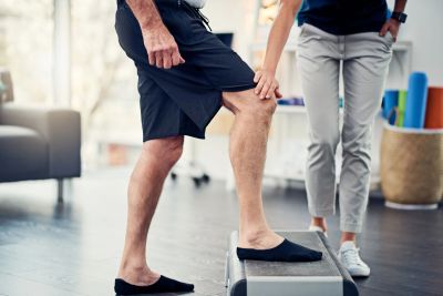 Physical therapy rehabilitation exercise with a step for a patient recoverying from total knee repla