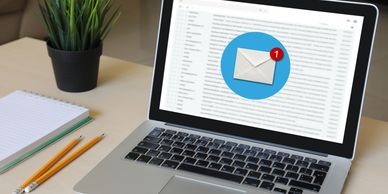 Laptop showing a new email notification with a plant and pencils nearby.