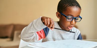 Young boy with glasses focused on reading and studying.