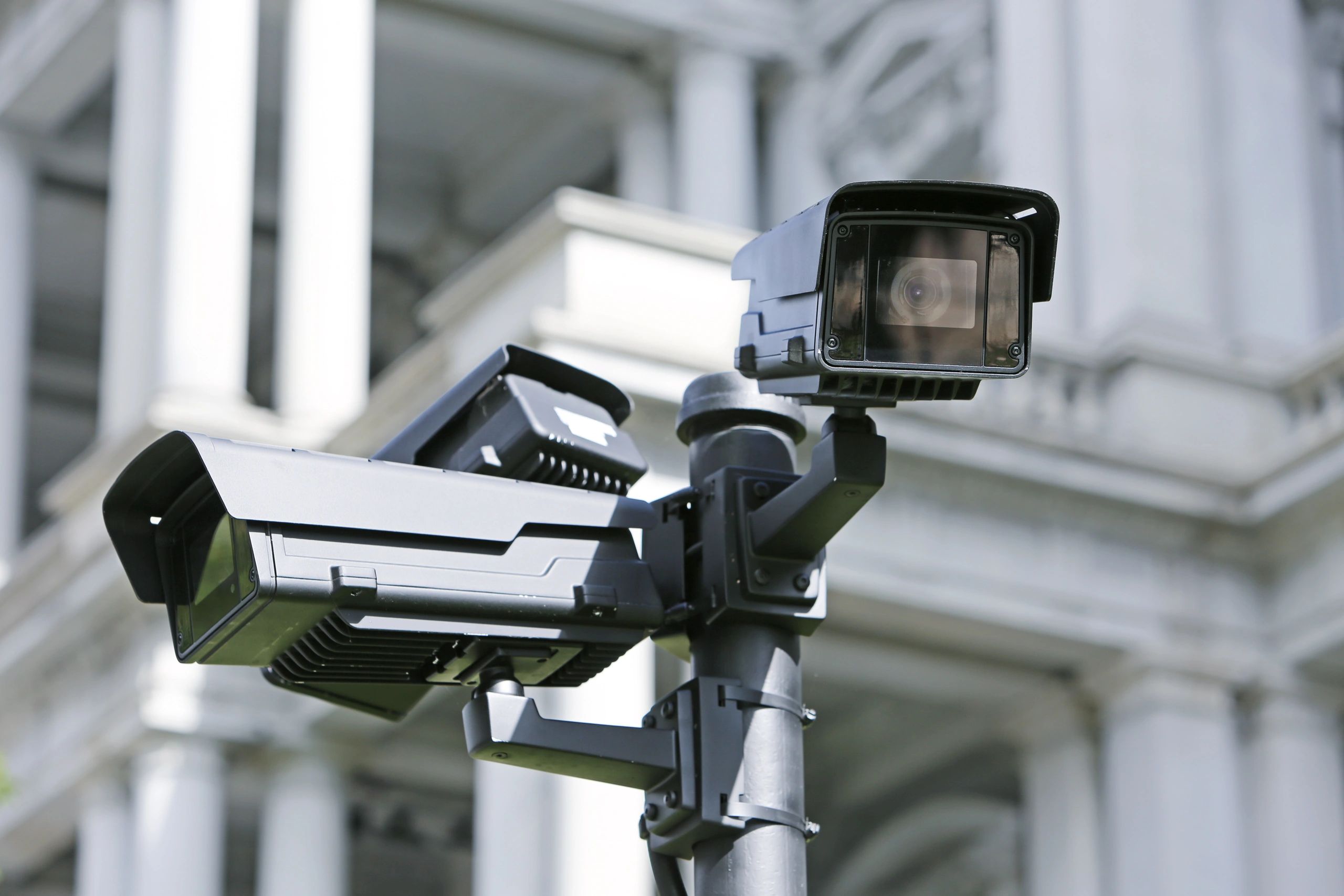Two black security cameras mounted outdoors.