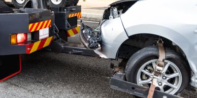 Damaged car being towed by a tow truck.