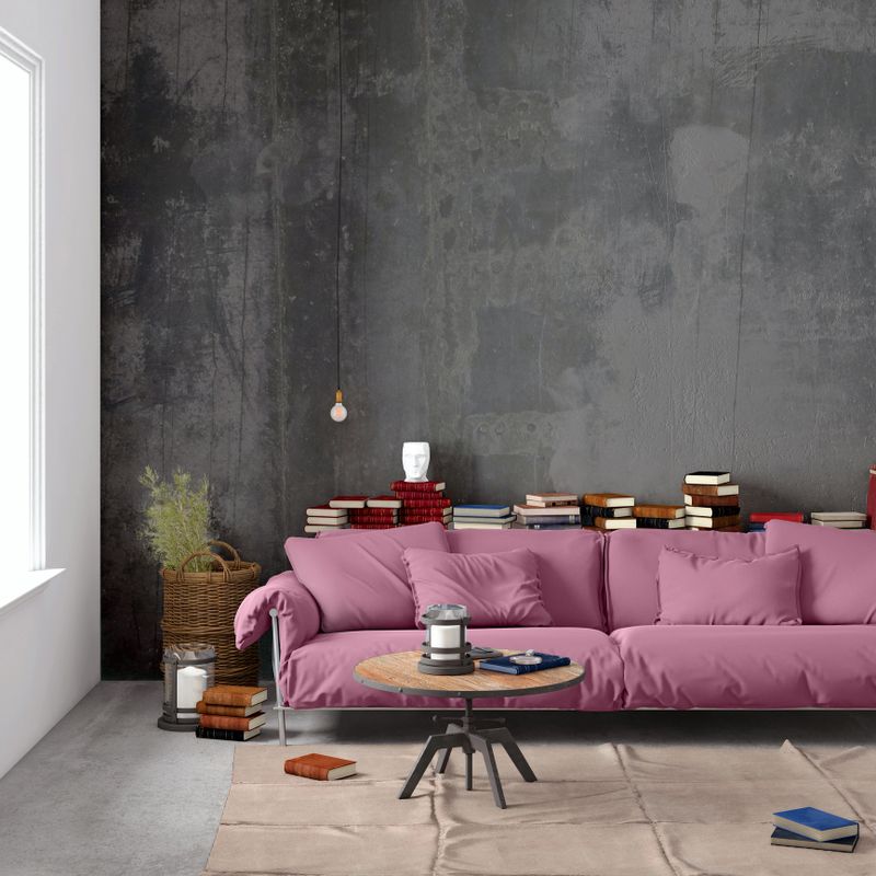 Modern Nordic Scandinavian styled apartment with pastel colored large sofa and blank wall behind. Living room scenery with concrete textured wall, concrete floor with carpet, big window, electric lamp, coffee table, plant, books and lots of other details. Copy space mock-up for designers.