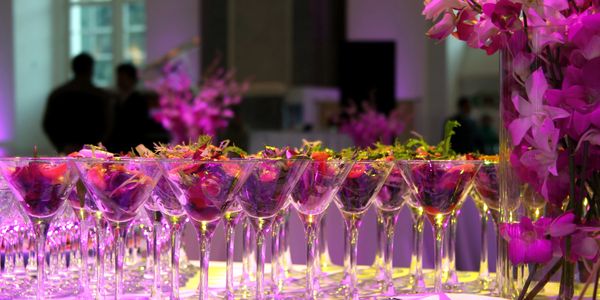 Rows of colorful cocktails in martini glasses at a decorated event.