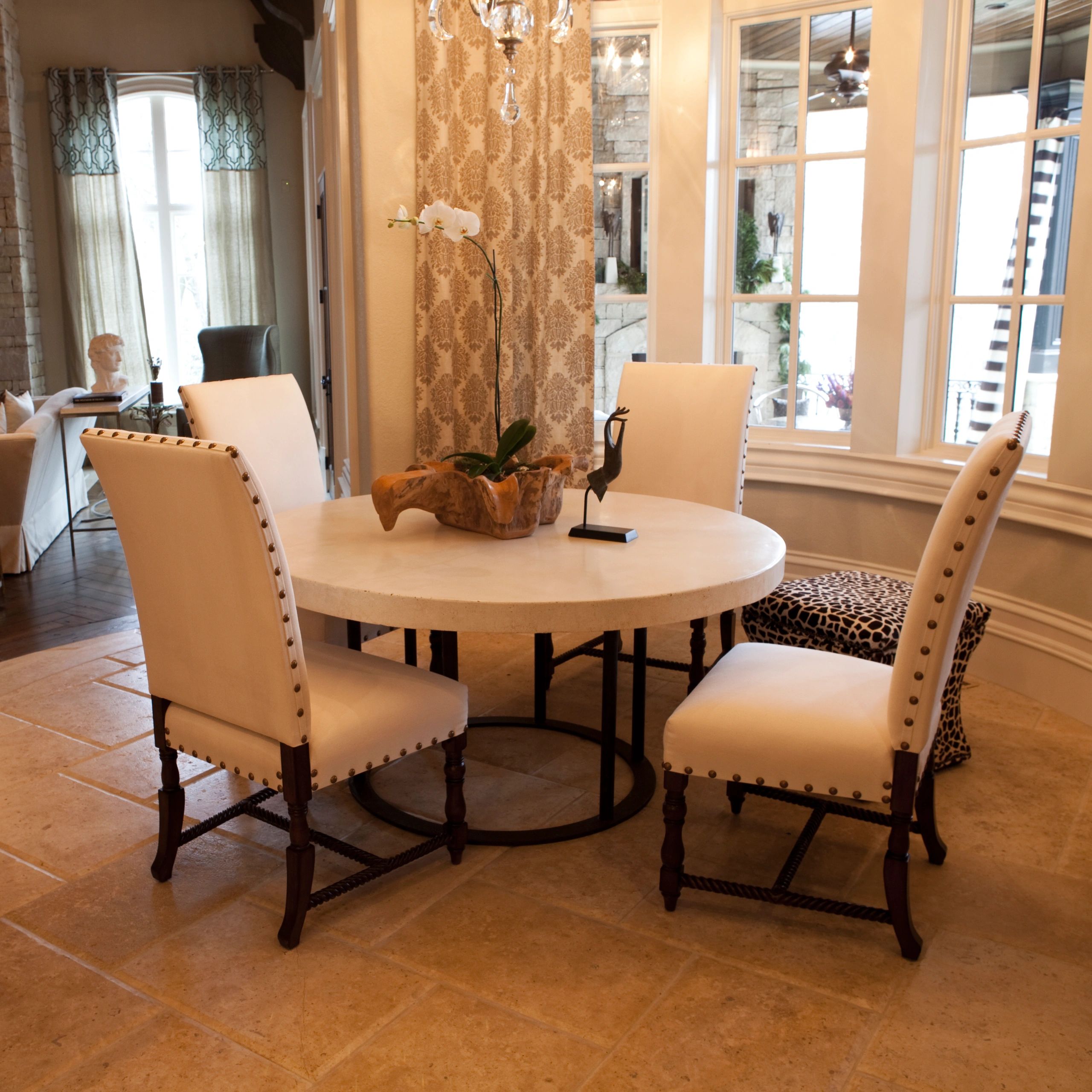 Elegant dining area with white chairs and a round table centerpiece.