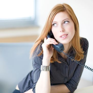 Young woman talking on a corded phone with a thoughtful expression.