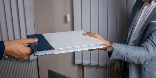 Two people exchanging a document folder.