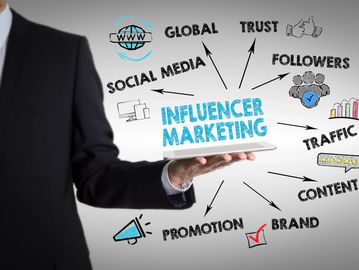 Businessman holding a tablet with influencer marketing concept words and icons.