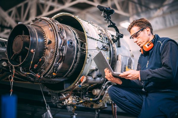 Technician disassembling large jet engine.
