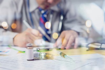 Professional writing down on clipboard with sample vials near the clipboard