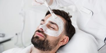 Man receiving a facial mask treatment.