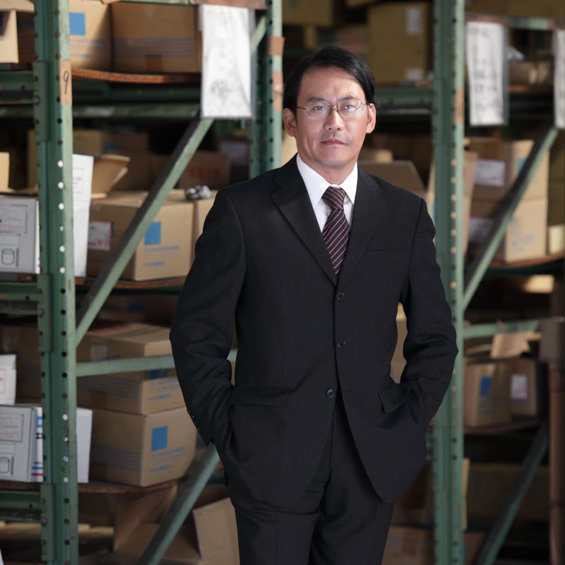 Japanese CEO in his warehouse posing proudly.