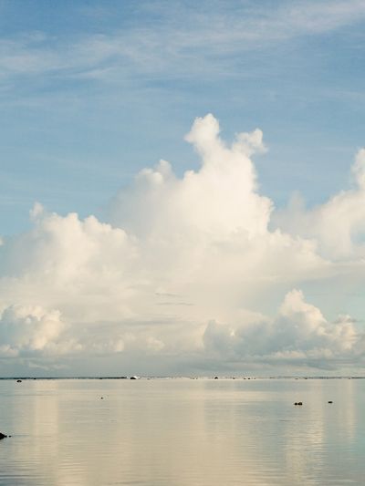Calm sea under a vast sky with fluffy clouds.